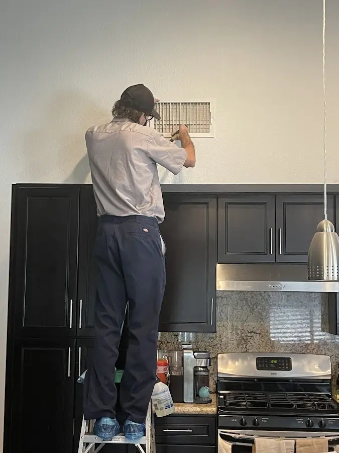 Technician inspecting an air vent during HVAC service in Columbiana